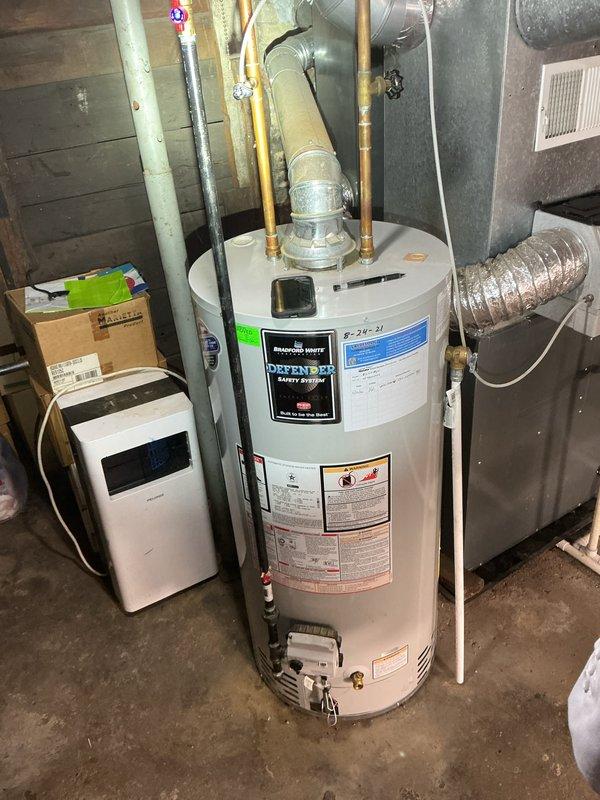 Completed rental inspection of water heater and furnace at residential property. Water heater identified as Defender Safety System model with installation date of 8-24-21 and recent service performed on 5/18/24. Documented 7-year-old Amana furnace and photographed all equipment conditions for rental property records.