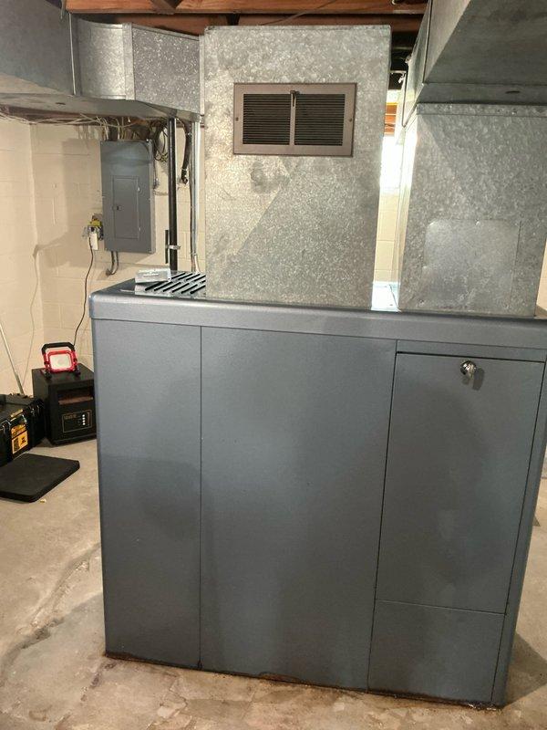 Conducted on-site assessment for complete HVAC system replacement in residential basement. Evaluated existing Janitrol furnace and 2001 AC unit, both at end of serviceable life. Documented current equipment configuration including gray metal furnace cabinet with flexible duct connections, copper refrigerant lines, condensate pump assembly, and existing ductwork infrastructure. Photographed installation area showing foam insulation panels, return air grille placement, electrical panel proximity, and available workspace for new equipment. Provided comprehensive estimate for new furnace and air conditioning system installation.