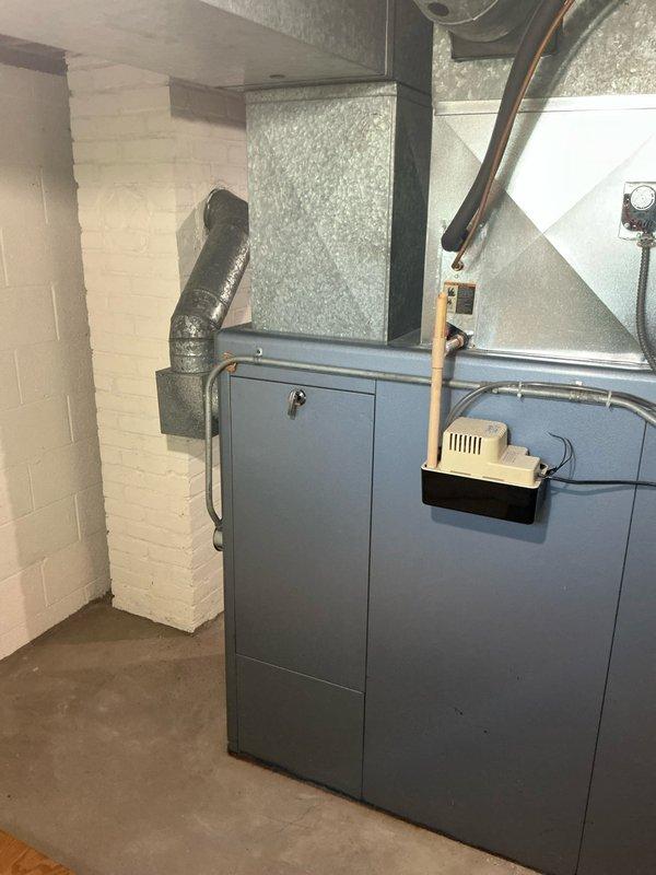 Conducted on-site assessment for complete HVAC system replacement in residential basement. Evaluated existing Janitrol furnace and 2001 AC unit, both at end of serviceable life. Documented current equipment configuration including gray metal furnace cabinet with flexible duct connections, copper refrigerant lines, condensate pump assembly, and existing ductwork infrastructure. Photographed installation area showing foam insulation panels, return air grille placement, electrical panel proximity, and available workspace for new equipment. Provided comprehensive estimate for new furnace and air conditioning system installation.