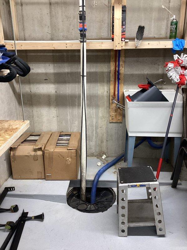 Conducted on-site assessment of existing sump pump system in basement/garage area. Evaluated current installation configuration, discharge piping, and electrical connections. Documented existing conditions with detailed photography showing workspace layout, overhead framing with insulation, concrete block foundation walls, and current equipment positioning. Provided comprehensive estimate for system upgrade or replacement to address operational concerns.