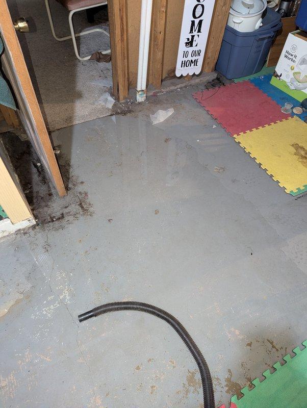 # AC Annual Cooling Maintenance - 16-Year-Old System

Completed comprehensive annual cooling maintenance on a 16-year-old air conditioning system. Upon arrival, discovered significant water accumulation on basement floor near HVAC equipment area, with moisture present around utility room perimeter and door frame base. Flexible drainage hose was positioned on floor, indicating recent water management efforts.

Inspected overhead plumbing and refrigerant line infrastructure in basement ceiling area. Examined copper refrigerant lines showing age-appropriate patina and verified integrity of all pipe joints and connections. Assessed flexible refrigerant line insulation and securing points, noting dark tape wrapping at multiple locations along the line set. Confirmed proper mounting and support of all overhead mechanical systems against floor joists.

Performed standard AC tune-up procedures including system performance evaluation, refrigerant pressure checks, and operational testing of all 