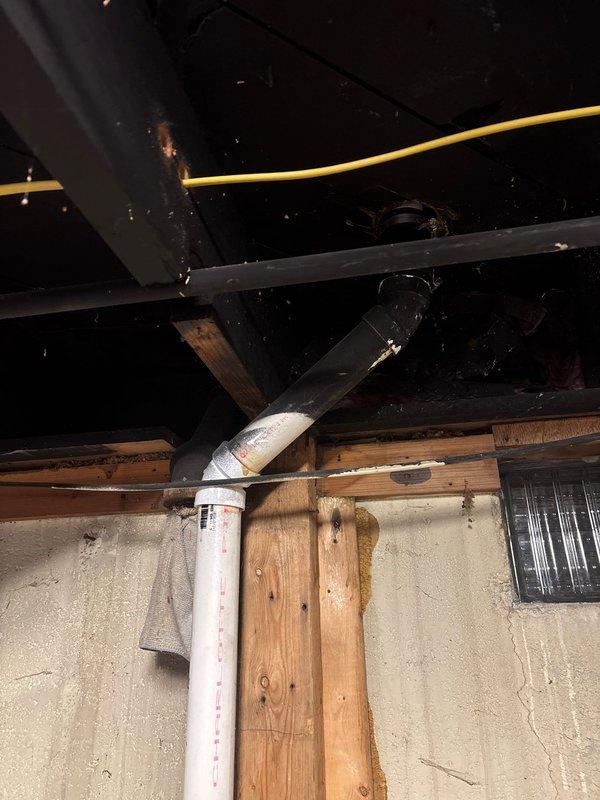 Responded to service call regarding abandoned plumbing vent system requiring assessment and estimate for restoration. Conducted thorough inspection of kitchen area and crawlspace to evaluate existing vent configuration and determine scope of work needed to bring system into proper working condition. Documented current plumbing vent installation showing PVC pipe assembly with elbow connection and partial insulation wrap in crawlspace area beneath kitchen sink location. Assessed accessibility, structural considerations, and code compliance requirements for reactivating the abandoned vent line. Photographed existing conditions including kitchen sink setup and underside plumbing infrastructure to support estimate preparation for necessary repairs and modifications to restore full vent functionality.