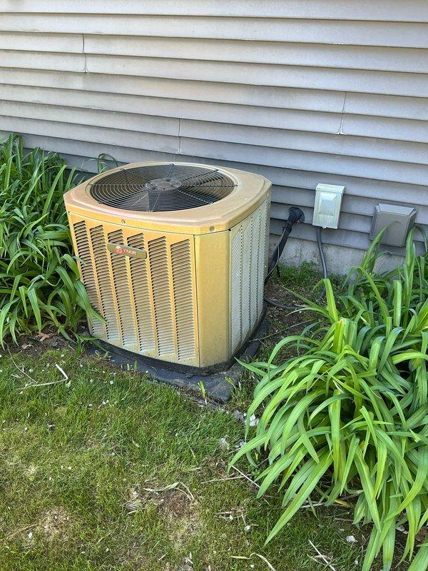 Conducted comprehensive assessment of residential HVAC system including outdoor condenser unit and indoor furnace equipment. Documented existing weathered yellow-cased air conditioning unit with vertical louvers positioned on exterior pad, along with basement heating equipment and associated plumbing connections. Customer expressed uncertainty about air conditioning system functionality requiring diagnostic evaluation and estimate preparation for potential repair or replacement services.