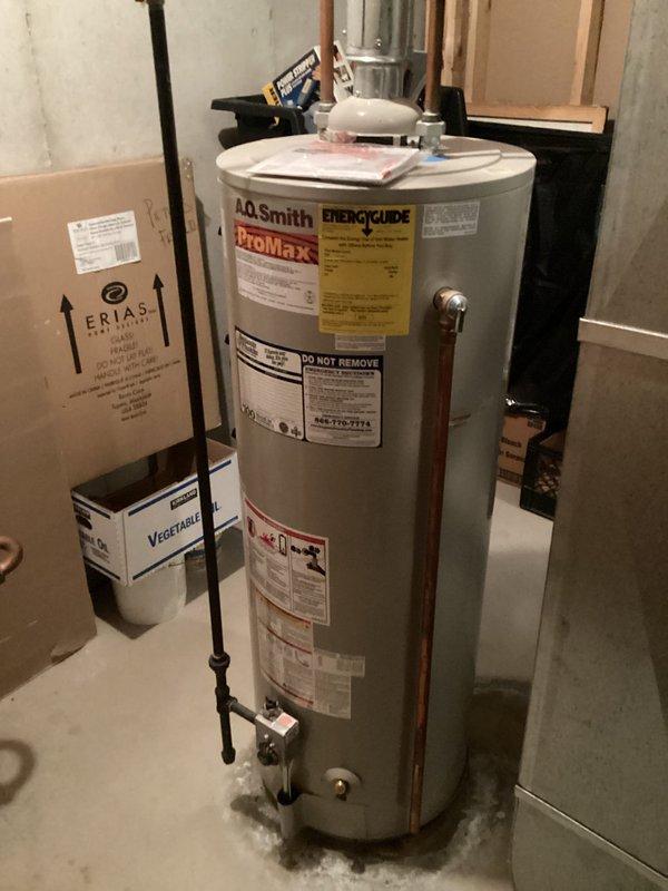 Responded to service call for water leaking from bottom of 20-year-old A.O. Smith ProMax water heater. Upon inspection, determined that the unit had reached end of serviceable life with tank leakage occurring at base, which is not repairable. Discussed repair versus replacement options with client, explaining that bottom tank leaks indicate internal corrosion and structural failure requiring full unit replacement rather than component repair. Documented existing installation with copper supply lines and proper venting configuration for replacement planning purposes.