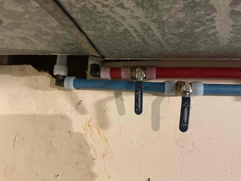 Completed partial repipe of residential plumbing system, installing new hot and cold water supply lines in basement utility area. Work included running new PEX piping (red for hot water, blue for cold water) with proper mounting brackets and securing all lines to structural members. Created wall access points through drywall to route new supply lines through existing wall cavities, working around existing electrical conduits and framing. All new pipe connections were properly fitted with appropriate fittings and tags for system identification.