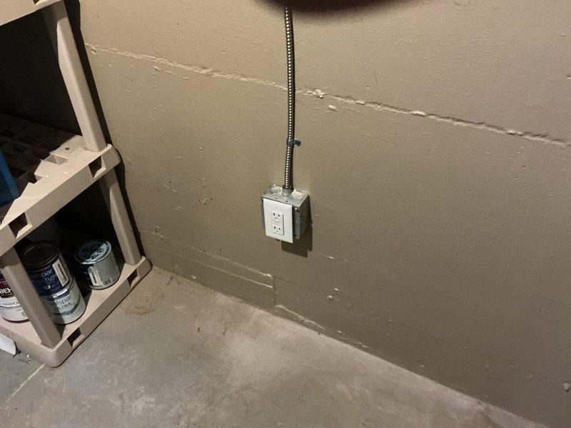Installed one GFCI outlet in basement utility area for sump pump protection per quoted scope. Ran flexible metal conduit from new outlet box to power source, properly securing all components to wall surface. All work completed in accordance with electrical code requirements.