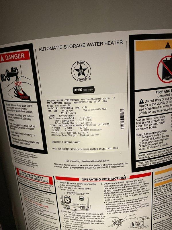 Completed installation of a 40-gallon tall natural gas water heater manufactured by Bradford White Corporation in basement utility area. Unit was properly positioned, connected to existing copper supply lines with brass fittings and valves, and vented through metallic exhaust vent pipe in accordance with manufacturer specifications and local code requirements.