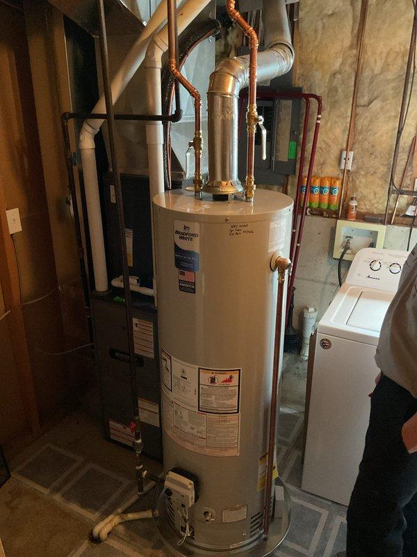 Completed installation of a 40-gallon tall natural gas water heater manufactured by Bradford White Corporation in basement utility area. Unit was properly positioned, connected to existing copper supply lines with brass fittings and valves, and vented through metallic exhaust vent pipe in accordance with manufacturer specifications and local code requirements.