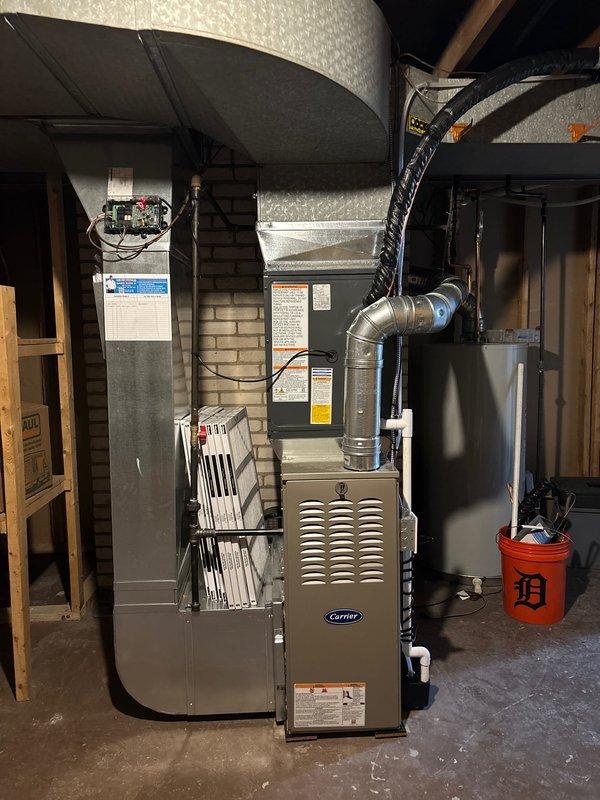 Successfully completed add-on air conditioning installation to existing Carrier furnace system in basement mechanical room. Installed new air handler unit adjacent to existing heating equipment, integrated cooling coil with furnace plenum, and connected metallic supply ductwork. Ran refrigerant line set from basement through exterior wall to outdoor condensing unit location at building foundation. Established proper drainage routing utilizing existing downspout system and corrugated drain lines. Completed all electrical connections, tested system operation, verified proper airflow and refrigerant charge, and confirmed integration with existing HVAC controls for seamless heating and cooling functionality.