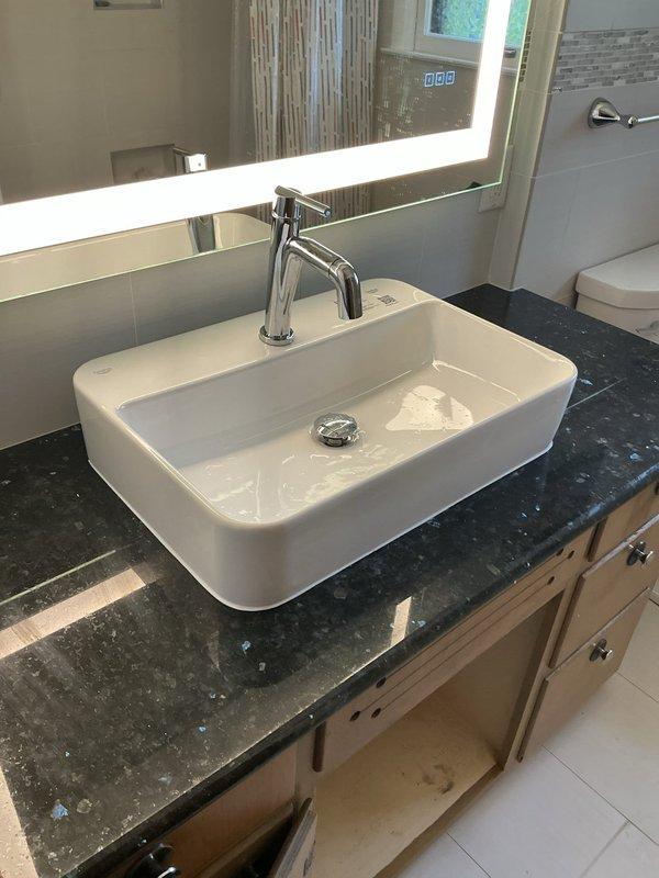 Completed installation of white rectangular vessel sink on existing granite countertop with contemporary chrome single-handle faucet. Installed new hot and cold water supply valves and lines to serve the vessel sink fixture. Capped unused water line in basement as requested, which was previously controlled only by shutoff valve. All plumbing connections tested and verified leak-free, with proper water flow and drainage confirmed at the new vessel sink installation.