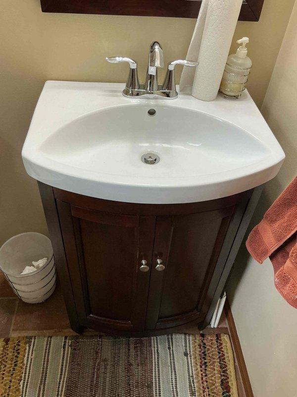 Installed chrome two-handle centerset faucet on bathroom vanity with white ceramic sink basin. Faucet was properly mounted, supply lines connected, and system tested to ensure proper water flow and no leaks.