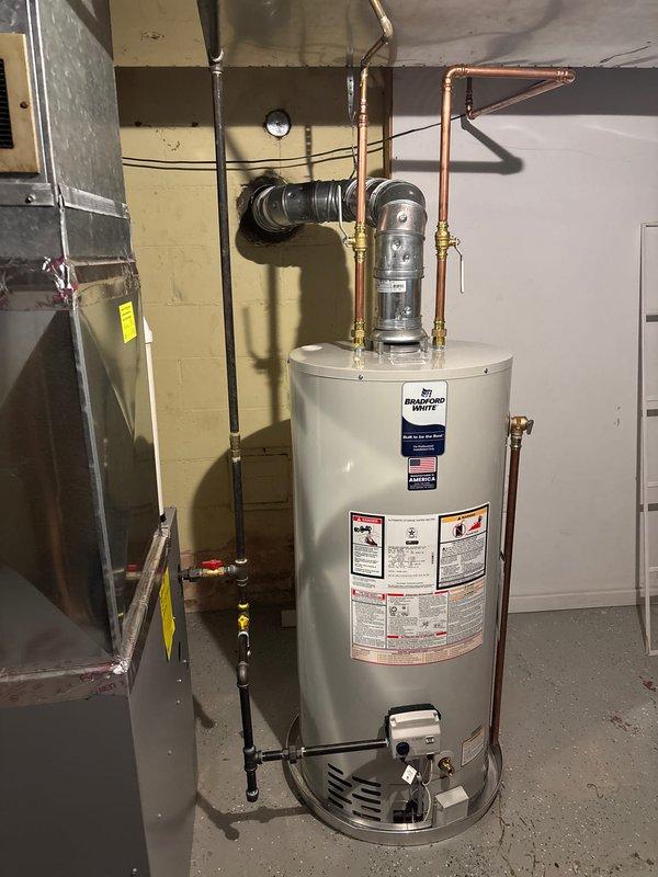 Completed installation of a 40-gallon Bradford White natural gas water heater (Model CCS6879647) with 40,000 BTU/hr input and 36,000 BTU/hr output capacity in basement utility area. Connected all copper water supply lines with brass fittings and valves, installed pressure relief valve and expansion tank on top of unit, and connected black flexible flue ductwork to existing ventilation system. Routed gas lines to unit and verified all connections for proper operation and safety compliance per manufacturer specifications.