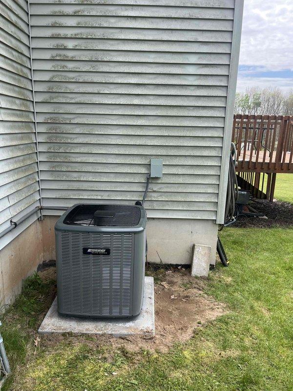 Completed full air conditioning system replacement at residential property. Removed existing outdoor condensing unit and installed new gray/silver outdoor AC unit on concrete pad with proper electrical disconnect box and conduit installation mounted to exterior siding. Indoor installation included new furnace unit with integrated cooling coil in mechanical room, complete with PVC venting and drainage piping configured for proper system operation. All electrical connections, refrigerant lines, and system controls were installed to manufacturer specifications. System was started up, tested for proper operation, and left running efficiently.