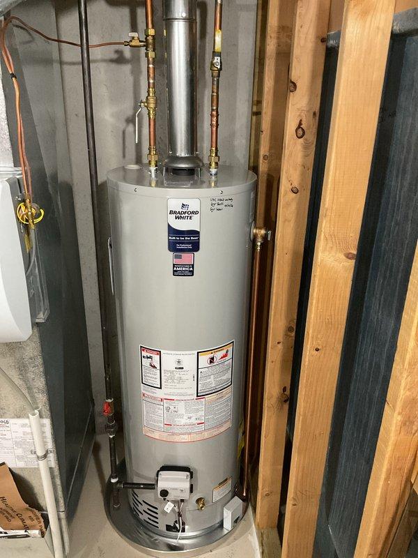 Completed installation of a 40-gallon natural gas Bradford White water heater in residential utility space. Unit was properly positioned, connected to existing copper supply lines with brass fittings and shut-off valves, vented with appropriate flue piping, and installed per manufacturer specifications and local code requirements.