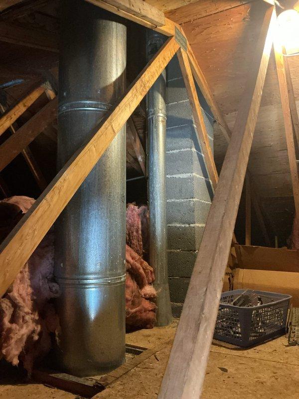 Responded to service call regarding home inspector's report of cracked exhaust pipe in attic space. Inspected 6-year-old water heater exhaust vent system running through attic and wall cavity. Upon visual inspection, identified discoloration on lower section of metal vent pipe but found no visible cracks or separation at joints. Photographed vent pipe installation showing proper vertical routing through wooden framing members with appropriate clearances. Exhaust system appears structurally intact with all connections secure. Documented condition for client records.