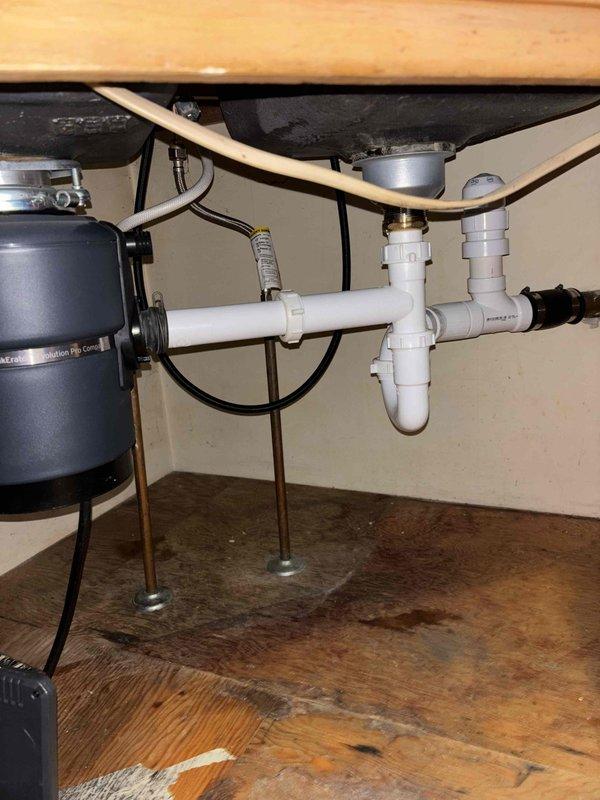 Completed kitchen sink drain line replacement and repiping project in accordance with Michigan plumbing code. Removed existing drain assembly and installed new PVC drain system under kitchen sink, including P-trap configuration with proper venting and connections to accommodate garbage disposal unit. Extended new PVC drain lines through basement ceiling joists to tie into main drainage system. All joints properly solvent-welded and secured with appropriate hangers and supports. System tested for leaks and proper drainage flow. Installation includes 1-year workmanship guarantee.