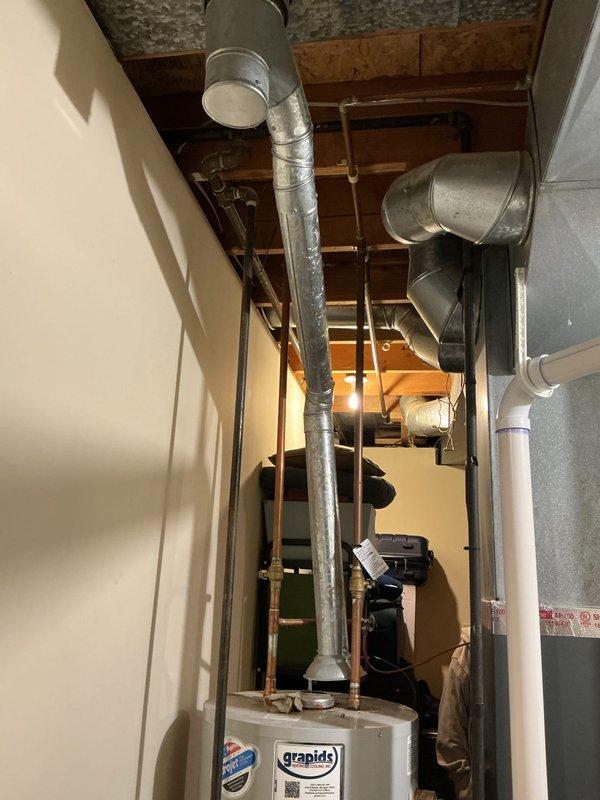 Responded to service call for complete loss of hot water due to extinguished pilot light on 39-year-old residential water heater. Upon arrival, inspected water heater and confirmed pilot light was out with no hot water production throughout the home. Successfully relit pilot light, verified proper ignition and flame characteristics, and tested unit operation to ensure restoration of hot water service. Documented equipment condition and mechanical room configuration showing water heater installation alongside furnace system with associated plumbing and ductwork connections.
