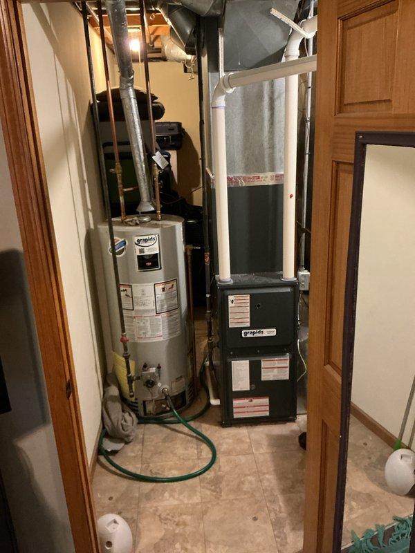 Responded to service call for complete loss of hot water due to extinguished pilot light on 39-year-old residential water heater. Upon arrival, inspected water heater and confirmed pilot light was out with no hot water production throughout the home. Successfully relit pilot light, verified proper ignition and flame characteristics, and tested unit operation to ensure restoration of hot water service. Documented equipment condition and mechanical room configuration showing water heater installation alongside furnace system with associated plumbing and ductwork connections.
