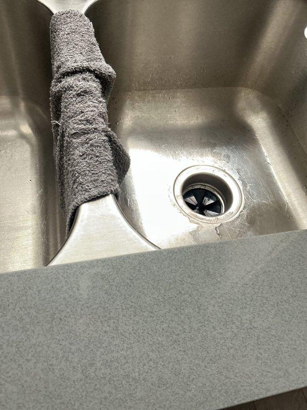 Responded to emergency service call for failed garbage disposal unit. Upon arrival, inspected kitchen sink disposal system and confirmed unit was inoperative. Removed existing black garbage disposal from undermount stainless steel sink basin. Disconnected electrical supply and plumbing connections including discharge drain line and dishwasher inlet. Installed new garbage disposal unit with proper mounting assembly to sink flange. Connected power cord and verified electrical connection. Attached discharge plumbing to existing PVC drain system and secured all connections. Tested unit for proper operation, checked for leaks, and confirmed disposal functions correctly. Cleared work area and returned cabinet to service.