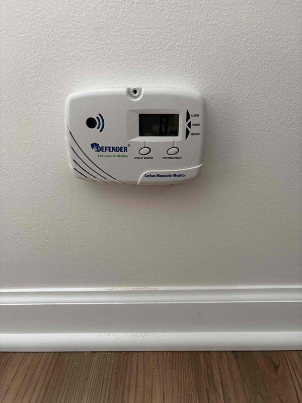 Responded to service call for furnace not heating with alarm sounding. Upon arrival, found carbon monoxide detector in alarm state displaying 000 ppm reading. Inspected Defender low-level CO monitor and internal circuit board components. Tested detector functionality using test/reset button and verified power supply and sensor operation. Determined alarm was triggered but CO levels returned to safe readings. Reset carbon monoxide detector and verified proper operation of all indicator lights and alarm functions. Advised on proper CO detector maintenance and monitoring procedures.