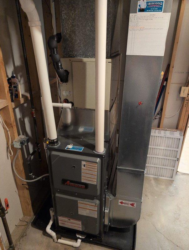 Completed full furnace installation in basement utility area. Installed new gray metal furnace unit with proper venting using white PVC piping extending vertically from the unit. Connected air handler/filter cabinet to system and ensured proper integration with existing ductwork, including rectangular and round flexible ducts. Verified all manufacturer specifications and safety requirements were met. System tested and confirmed operational upon completion.