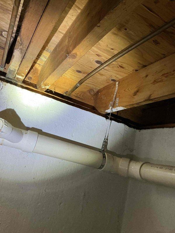 Responded to reported thumping noise occurring during toilet flushing and high water usage. Inspected basement plumbing infrastructure and identified water hammer issue in drainage system. Examined exposed PVC piping and support brackets in crawl space to assess pipe movement and securing points. Replaced deteriorated outdoor hose spigot that exhibited active leaking and corrosion. Removed old copper fixture from exterior wall and installed new frost-free sillcock with proper mounting and sealing to prevent future leaks.