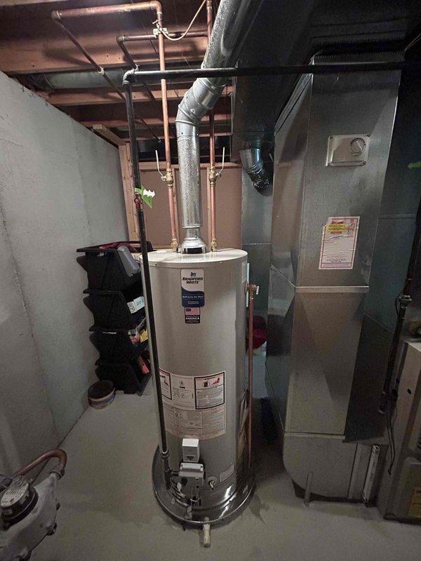 Successfully installed a Bradford White 50-gallon automatic storage natural gas water heater in the basement mechanical room. The unit was properly positioned and connected to existing copper supply lines and gas piping, with all connections secured and tested for leaks. Installed appropriate venting ductwork with metal elbows to ensure proper exhaust ventilation per manufacturer specifications. Verified all clearances meet minimum requirements for safe operation around adjacent HVAC equipment. Confirmed proper gas pressure, tested the burner ignition system, and verified temperature and pressure relief valve operation. All manufacturer labels, safety warnings, and AHRI certification documentation remain intact and visible on the unit exterior. System was fully tested and operational upon completion.