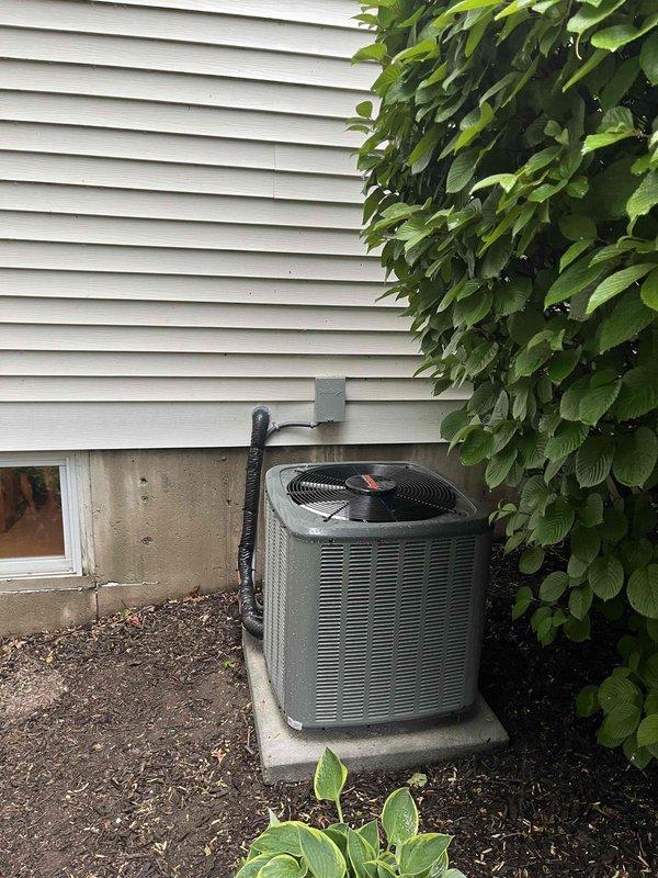 Completed full HVAC system installation including new furnace and air conditioning condenser unit. Installed outdoor AC condenser on concrete pad against exterior wall with proper refrigerant line routing secured to house exterior via mounting brackets. Indoor installation included new furnace in basement mechanical room with complete white PVC venting system, integrated Aprilaire whole-house humidifier, and all necessary ductwork connections. All equipment installed per manufacturer specifications with proper electrical connections, condensate drainage, and gas piping. System tested and verified operational upon completion.