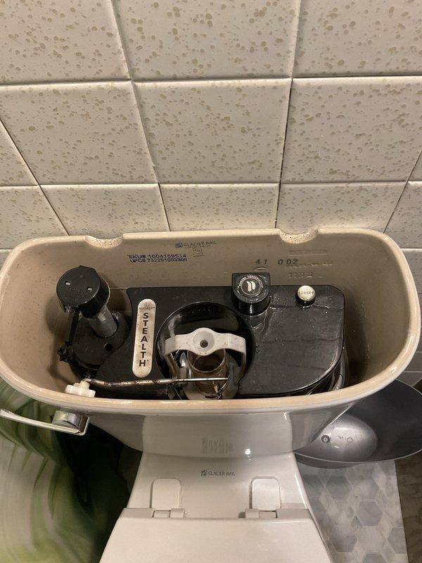 Responded to service call for multiple bathroom fixture issues including toilet running excessively, slow-draining sink, and malfunctioning tub spout diverter. Inspected toilet tank components and identified fill valve requiring adjustment to resolve extended running cycle. Addressed slow sink drainage issue and confirmed tub spout diverter mechanism was not properly redirecting water flow to showerhead. Documented existing conditions with photographs showing toilet tank internals with Stealth flush system components and vintage green bathtub with chrome fixtures and tile surround.