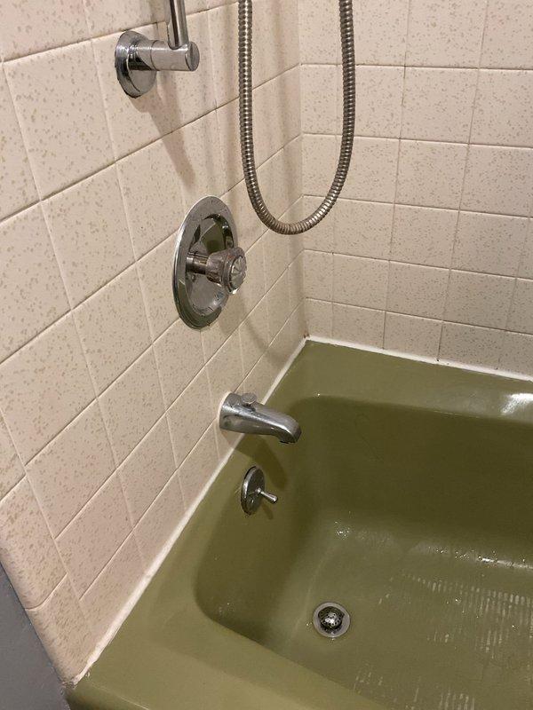 Responded to service call for multiple bathroom fixture issues including toilet running excessively, slow-draining sink, and malfunctioning tub spout diverter. Inspected toilet tank components and identified fill valve requiring adjustment to resolve extended running cycle. Addressed slow sink drainage issue and confirmed tub spout diverter mechanism was not properly redirecting water flow to showerhead. Documented existing conditions with photographs showing toilet tank internals with Stealth flush system components and vintage green bathtub with chrome fixtures and tile surround.