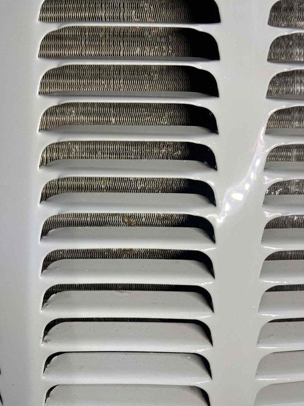 Completed comprehensive AC Super Tune-up on split system unit with 5-year energy efficiency service package. Performed full system inspection, cleaned evaporator coils visible behind white louvered grilles, verified proper airflow through ventilation components, and documented equipment condition with before/after photography showing clean, well-maintained grille assemblies and internal heat exchange components.