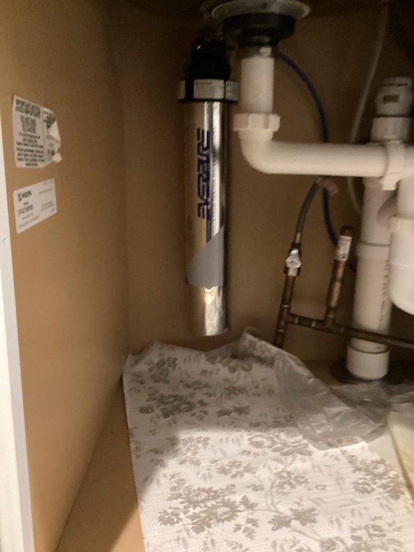 Conducted site assessment for installation of Everpure H-300 NXT water purification system beneath kitchen sink. Evaluated existing plumbing configuration including P-trap assembly, supply line connections, copper piping with shut-off valves, and available cabinet space for filter mounting. Documented current under-sink conditions showing adequate clearance for vertical filter installation alongside existing disposal unit and drain assembly. Confirmed compatibility of existing plumbing infrastructure with proposed water filtration system and identified connection points for cold water supply line integration.
