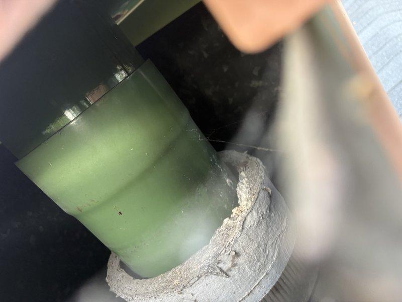 Responded to water leak complaint originating from flue system penetration at roof level. Upon inspection, identified previous amateur patch repair that had failed, allowing water intrusion during rain events. Documented existing conditions with photographs showing corroded flue components with significant oxidation and deterioration of metal surfaces. Measured affected area and assessed structural integrity of flue assembly and surrounding roofing materials. Flue pipe exhibited advanced corrosion with rust patina and surface pitting, indicating prolonged exposure to moisture. Roofing substrate around penetration showed water staining and weathering. Insulation wrap at base of flue component appeared compromised. Recommended complete flue system replacement rather than additional patching due to extent of corrosion and age of existing components to ensure permanent resolution of leak issue.