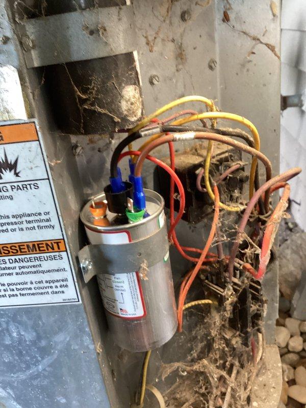 # AC No Cooling - 16 Year Old Amana System

Responded to service call for air conditioning system not cooling properly. Upon arrival, inspected 16-year-old Amana outdoor condensing unit located on exterior of residence.

**Inspection Findings:**
- Outdoor unit accessible with electrical disconnect and refrigerant lines properly installed
- Significant deterioration observed inside electrical compartment
- Extensive rust staining, dirt accumulation, and debris buildup throughout interior housing
- Capacitor and wiring connections inspected - multiple colored wire terminals present on cylindrical capacitor
- Evidence of moisture intrusion and environmental exposure causing interior component degradation

**Work Performed:**
- Performed visual inspection of outdoor condensing unit
- Opened electrical compartment to assess internal components
- Documented condition of capacitor, wiring, and interior housing
- Photographed equipment condition for service records
- Assessed overall system de