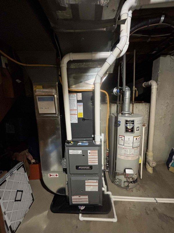 Completed full HVAC system replacement including outdoor condensing unit and indoor air handler. Removed existing equipment and installed new gray condensing unit on concrete pad with proper refrigerant line connections and electrical hookup. Installed new furnace/air handler in basement mechanical room with updated PVC venting system configured for proper exhaust and intake. Verified all refrigerant connections, tested system operation, and confirmed proper airflow throughout the system.