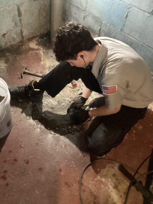 Installed new sump pump system in basement location where no existing crock or basin was present. Excavated concrete floor, set basin, installed pump with discharge line routed through foundation to exterior, and completed all necessary connections for proper drainage operation.
