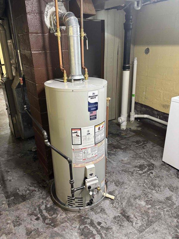 Successfully completed installation of a 40-gallon natural gas water heater in basement utility area. Removed existing unit and installed new short-height natural gas water heater with proper venting, copper supply line connections with brass fittings, and gas line hookup. All connections were secured and tested for proper operation and safety compliance.