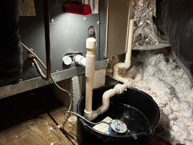 Responded to service call for blinking indicator light and water leakage from attic area on dual 18-year-old Goodman HVAC systems. Upon inspection, identified condensate drain issue causing water accumulation in emergency overflow pan. Cleared primary drain line blockage, verified proper drainage flow, and tested secondary safety switch operation. Confirmed both systems operating normally with no further leakage detected.