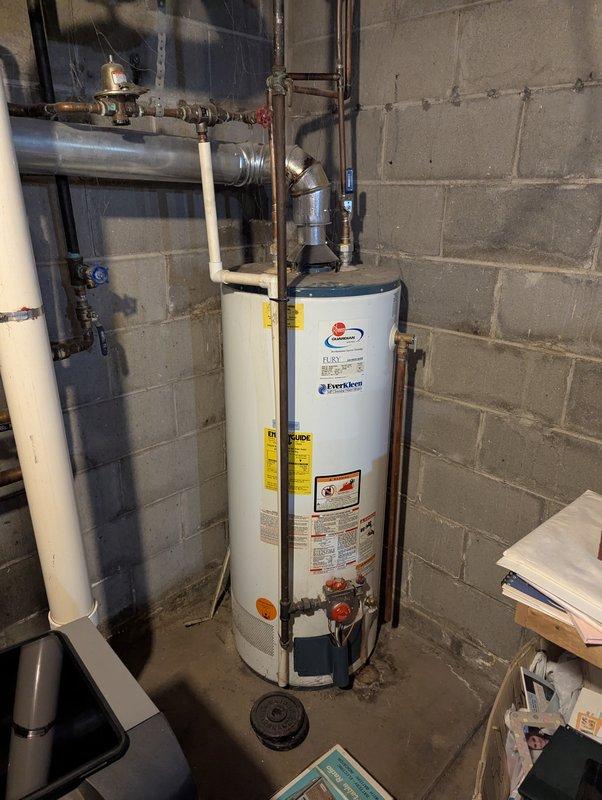 Responded to no cooling complaint on 31-year-old Bryant system. Upon arrival, performed diagnostic evaluation of air conditioning unit and associated components. Documented existing equipment conditions including basement utility area plumbing, water heater installation, and surrounding infrastructure with photographic evidence for service records.