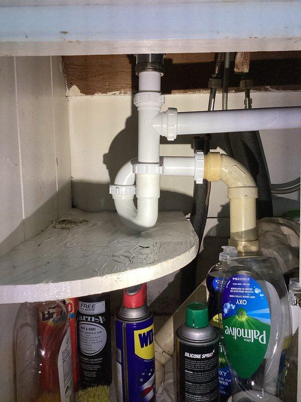 Responded to a leak at kitchen sink. Upon inspection, found the white PVC P-trap assembly beneath the sink had loose compression fittings causing water seepage. Tightened all slip joint connections on the P-trap assembly and verified proper seal at the metal sink drain coupling. Tested the drain system by running water through the sink to confirm leak was resolved and all connections remained dry under pressure.