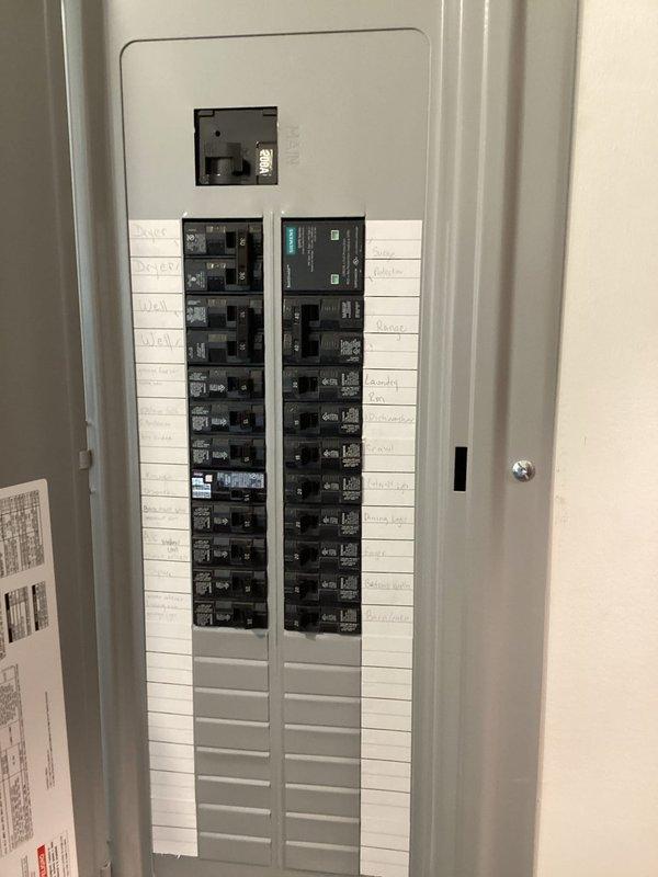 Completed quoted electrical panel inspection and documentation in utility room. Photographed main electrical panel showing dual columns of circuit breakers in serviceable condition with proper labeling on interior door. Documented existing wall penetration where copper piping passes through drywall near HVAC equipment, noting opening requires future repair to maintain building envelope integrity. All electrical components verified accessible and panel maintained in clean, operational condition.