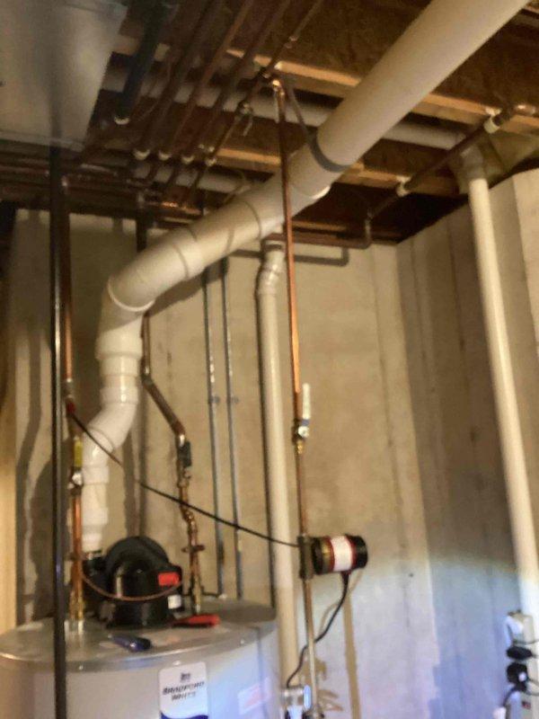 Responded to water heater leak at bottom of unit causing drip pan overflow. Upon inspection, confirmed Bradford White water heater manufactured in 2022 with partial replacement completed in 2024 under limited warranty coverage. Assessed severity of leak originating from tank base and determined internal tank failure requiring full unit replacement. Documented existing plumbing configuration including copper supply lines, circulation pump assembly, and PVC venting system for replacement specifications. Advised client that tank integrity compromise cannot be repaired and complete water heater replacement is necessary to resolve issue.