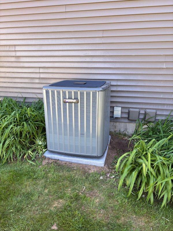 Completed full residential HVAC system installation including new Amana furnace and outdoor AC condenser unit. Furnace installed in interior mechanical room with proper venting using white PVC piping, connected to existing ductwork infrastructure, and integrated with water heater utilities. Outdoor condenser unit positioned on concrete pad against exterior wall with appropriate clearances, electrical disconnect box mounted, refrigerant lines and conduit properly routed through siding. All equipment secured, tested for proper operation, and system commissioned to manufacturer specifications.