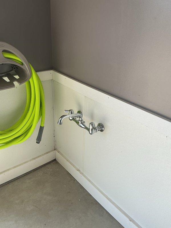 Responded to service call for two leaking exterior faucets at a 30-year-old residential property. Inspected wall-mounted chrome faucet assembly in utility room and traced supply lines through crawl space to identify source of leaks. Examined copper water supply pipes and connections where they pass through structural framing with insulation. Documented existing plumbing configuration and leak points with photographs for service records.