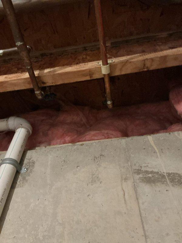 Responded to service call for two leaking exterior faucets at a 30-year-old residential property. Inspected wall-mounted chrome faucet assembly in utility room and traced supply lines through crawl space to identify source of leaks. Examined copper water supply pipes and connections where they pass through structural framing with insulation. Documented existing plumbing configuration and leak points with photographs for service records.