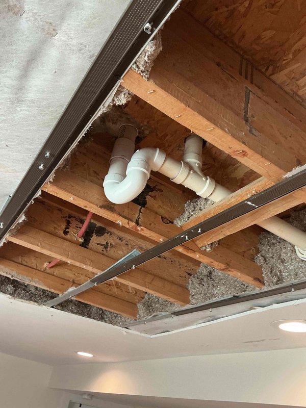 Completed installation of P-trap assembly in ceiling cavity plumbing system. Accessed work area through ceiling opening, installed white PVC P-trap configuration with proper fittings and connections to existing drain lines, ensuring code-compliant drainage and venting functionality.