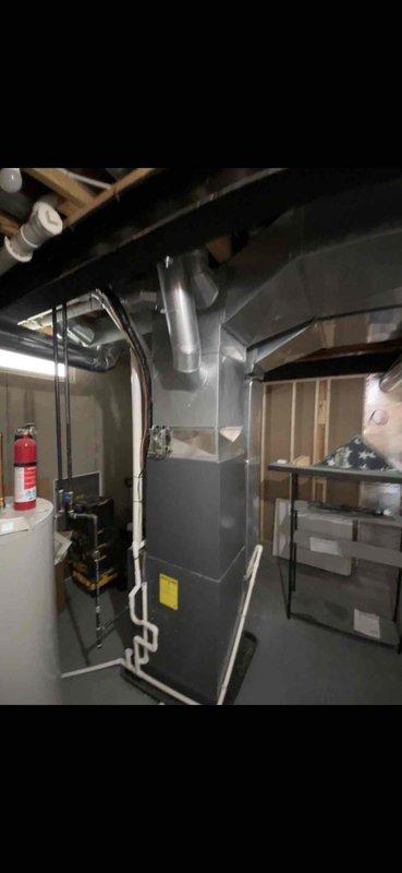 Completed full furnace and air handler installation in basement mechanical room. Installed new HVAC system including air handler unit with proper refrigerant line connections, ductwork integration using flexible and rigid metallic ducts, and white PVC condensate drainage piping. System positioned vertically in unfinished basement space with all electrical connections, ventilation infrastructure, and manufacturer specifications verified. All components properly mounted, secured, and tested for operational readiness.