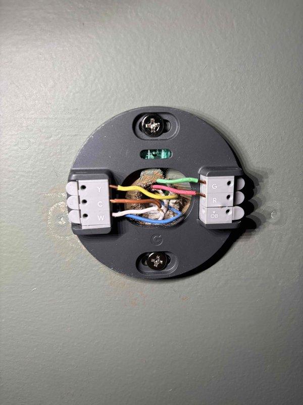 Responded to service call for Amana AC system displaying thermostat error code N260 indicating low voltage issue. Upon arrival, verified AC system was operational despite error code on 10-year-old unit. Inspected thermostat wiring at wall-mounted base and traced connections to control board terminals. Examined circuit board terminal connections including R, C, G, Y1, Y2, W1, W2, DHUM, and OB terminals to verify proper 24VAC supply and wiring integrity. Photographed thermostat base wiring configuration showing yellow, orange, pink, green, blue, and white conductors, and documented control board terminal connections. Tested voltage at thermostat and control board to identify source of low voltage condition. Confirmed all wire connections were secure at both thermostat mounting base and HVAC control board terminals. Cleared error code and restored normal thermostat operation.