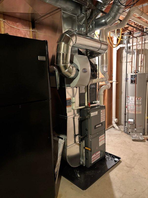 Completed full installation of new furnace and air conditioning system in basement utility area. Mounted furnace unit on platform with proper clearances, installed metallic ductwork system connecting to existing distribution network throughout ceiling joists, and configured white PVC condensate drainage piping with appropriate routing and pitch. Connected all electrical and gas lines per manufacturer specifications, verified proper venting installation, and tested system operation to ensure heating and cooling functionality. All equipment labeled and secured according to code requirements.