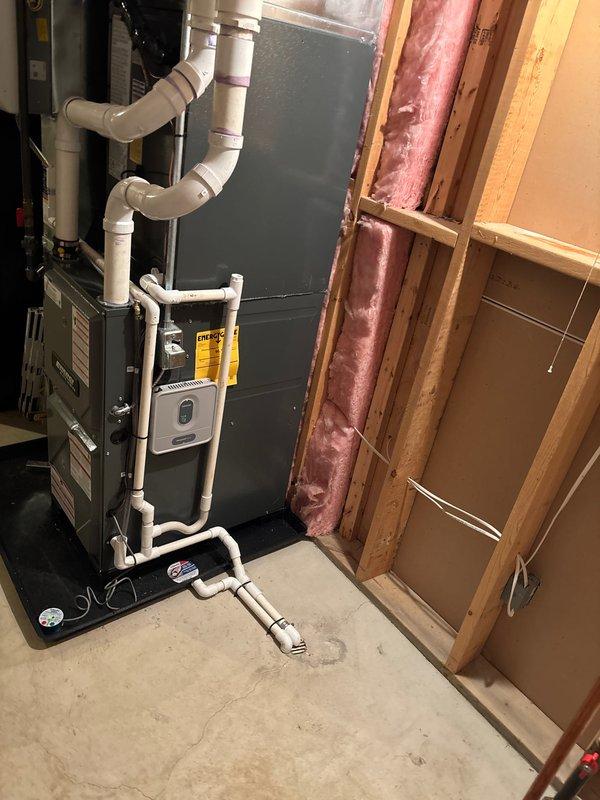Completed full installation of new furnace and air conditioning system in basement utility area. Mounted furnace unit on platform with proper clearances, installed metallic ductwork system connecting to existing distribution network throughout ceiling joists, and configured white PVC condensate drainage piping with appropriate routing and pitch. Connected all electrical and gas lines per manufacturer specifications, verified proper venting installation, and tested system operation to ensure heating and cooling functionality. All equipment labeled and secured according to code requirements.